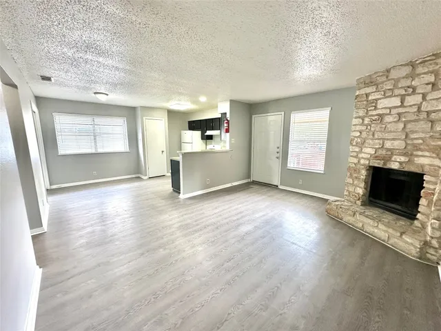 an empty room with windows fireplace and wooden floor