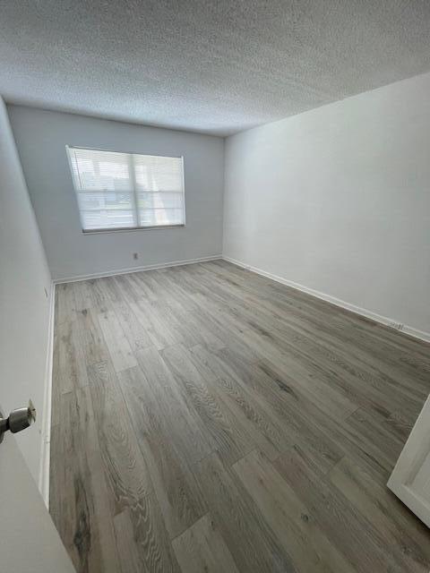 2075 Cornwall East, Unit 2075 Boca Raton, FL 33434 - Photo 17 of 32 an empty room with wooden floor and windows