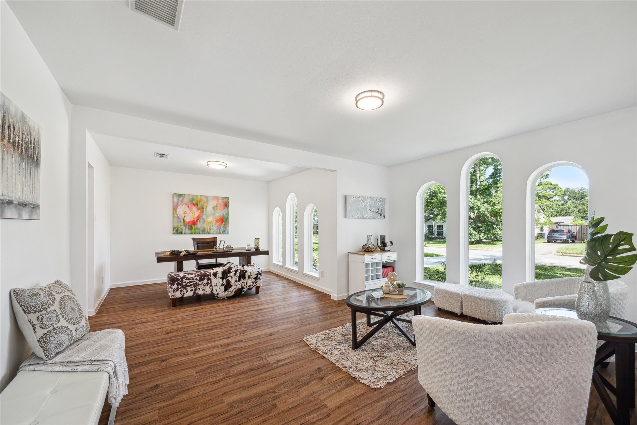 This flexible front living space is filled with natural light from a series of elegant arched windows that add charm and sophistication. Whether used as a formal sitting area or home office, the space offers beautiful street views, updated lighting, and seamless flow with rich wood-look flooring throughout.