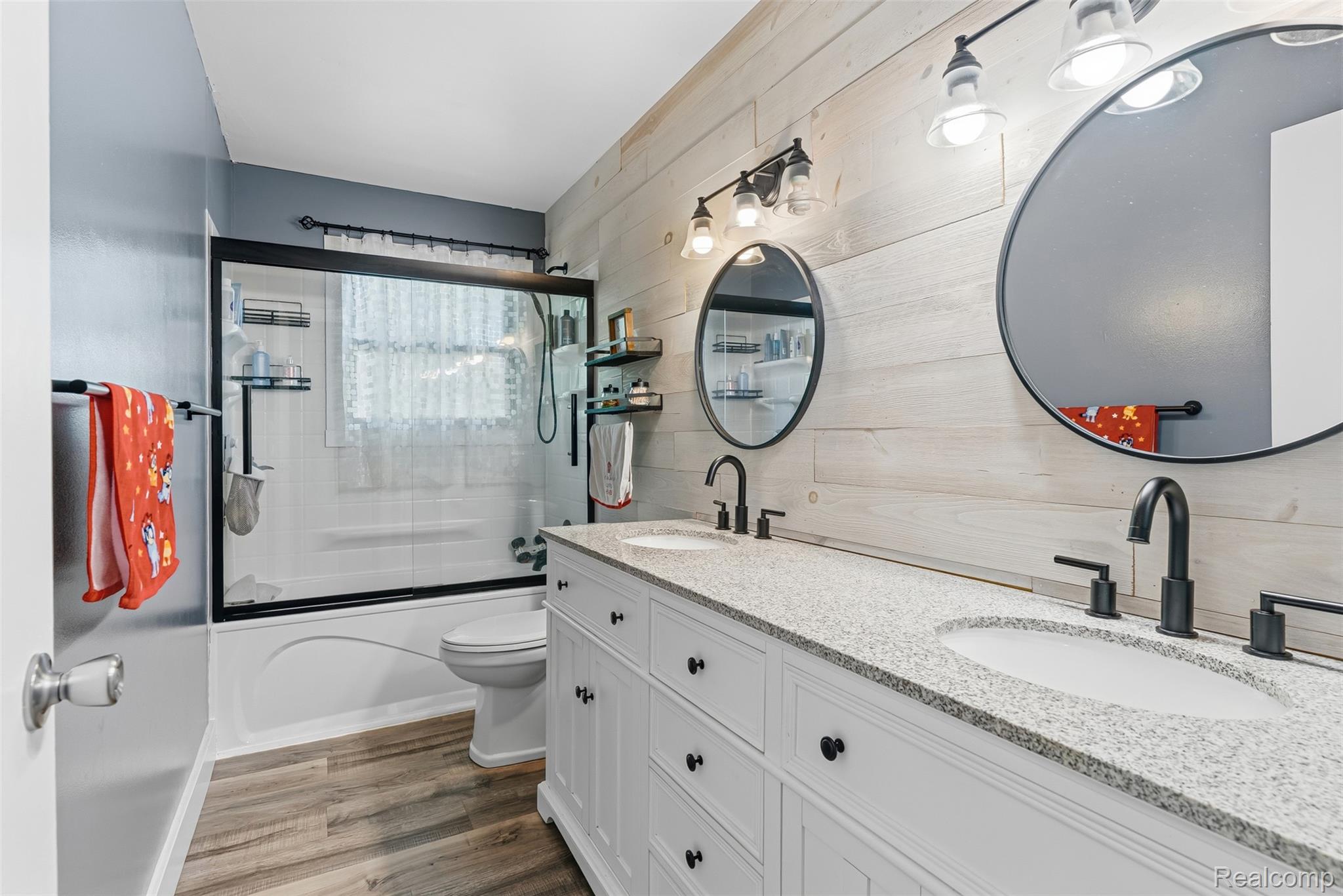 14433 Tuscola Road Clio, MI 48420 - Photo 23 of 43 Bathroom with combined bath / shower with glass door, double vanity, dark wood-style flooring, and wood walls