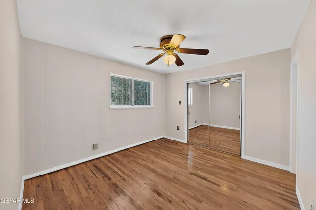 a view of empty room with wooden floor and fan