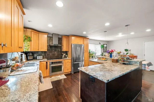a kitchen with stainless steel appliances granite countertop a sink a stove and a wooden cabinets