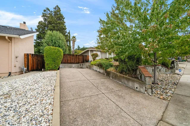 a view of a house with a small yard and large tree