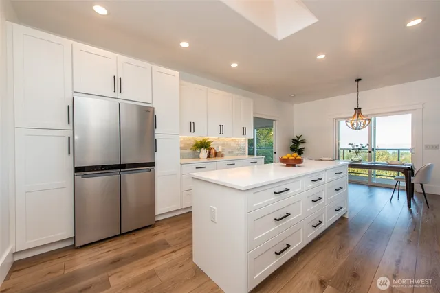 a kitchen with a refrigerator a white table and chairs