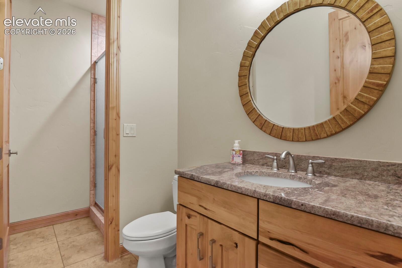 5545 Wilson Road Colorado Springs, CO 80919 - Photo 24 of 48 Main level bathroom featuring a wood-finish vanity cabinetry with stone countertop and undermount sink and free standing shower.