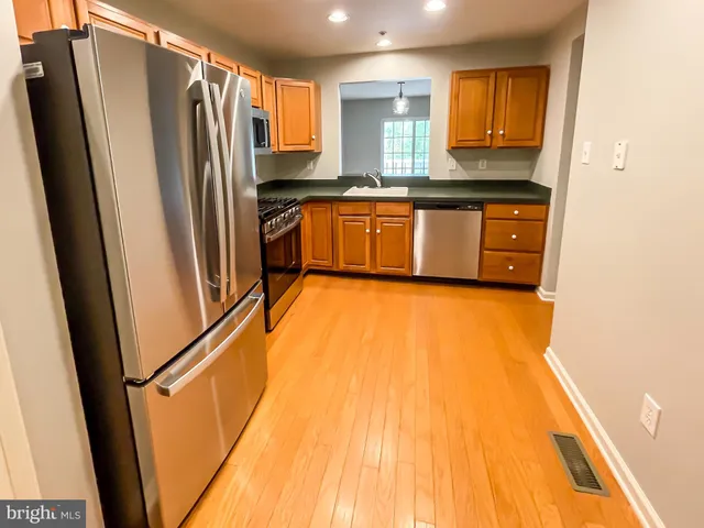 a kitchen with stainless steel appliances granite countertop a refrigerator a sink and white cabinets