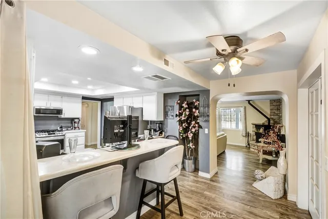 a kitchen with stainless steel appliances kitchen island granite countertop a table chairs in it and wooden floors
