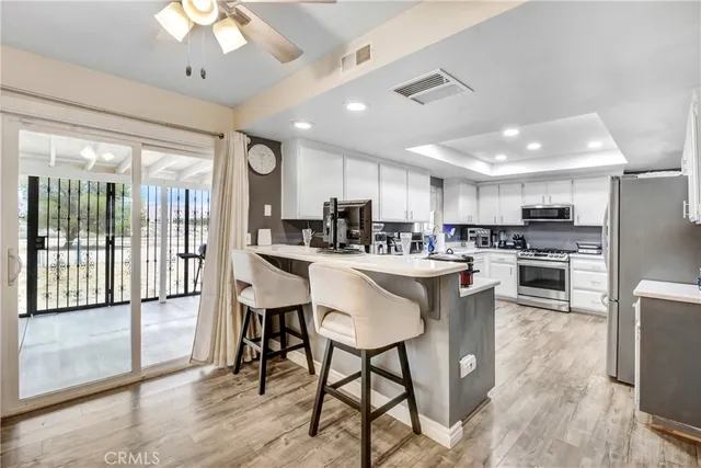 a kitchen with stainless steel appliances kitchen island granite countertop a refrigerator a stove a sink a dining table and chairs with wooden floor