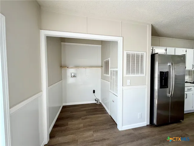 a view of a hallway with wooden floor and a refrigerator