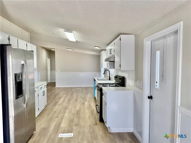 a kitchen with stainless steel appliances granite countertop a refrigerator a stove and a sink