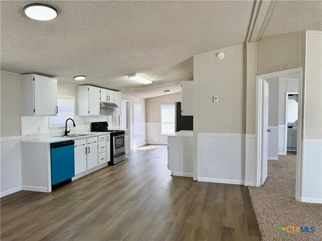 a large kitchen with cabinets wooden floor and stainless steel appliances