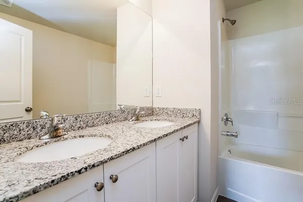 a bathroom with a granite countertop sink toilet vanity mirror bathtub and shower
