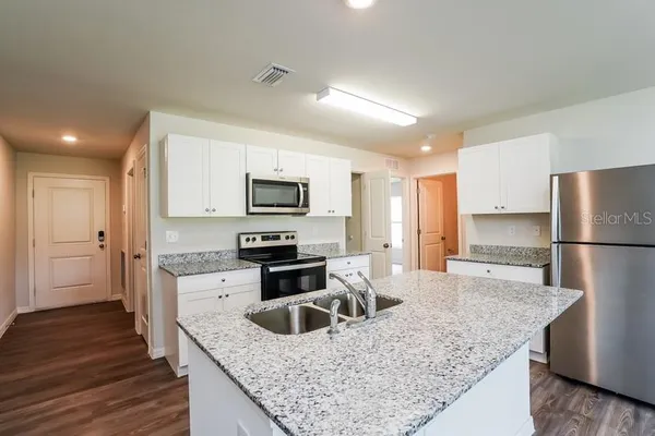 a kitchen with granite countertop a sink stove and refrigerator