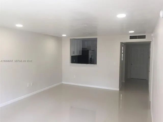 a view of an empty room with window and bathroom