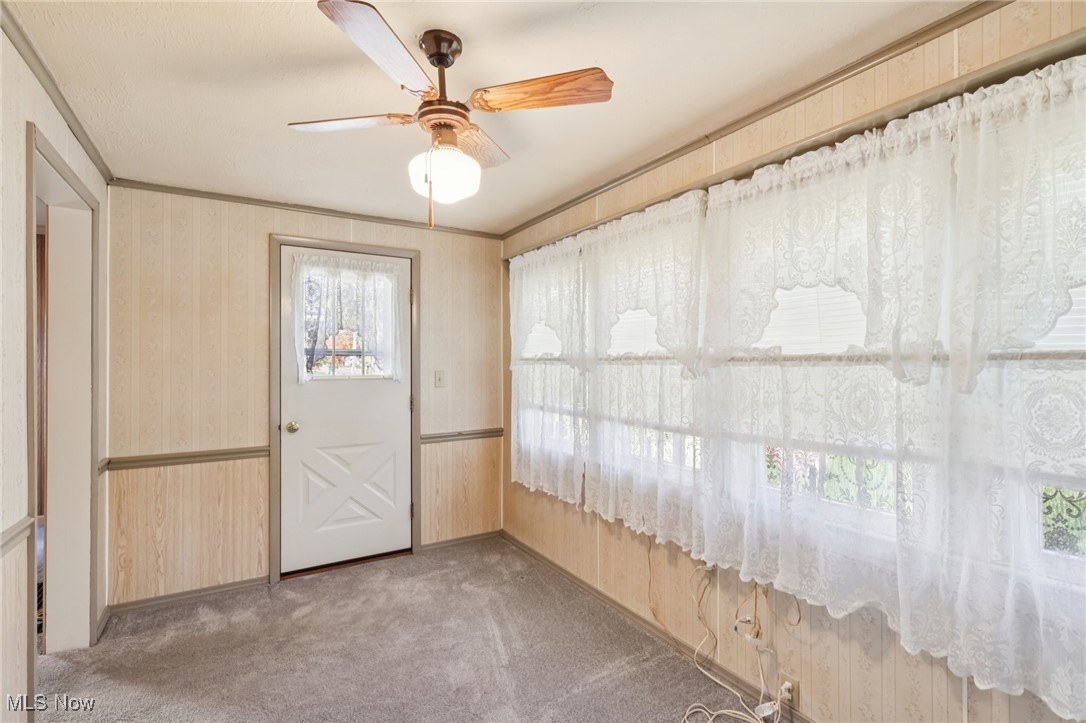 6235 Jefferson Road Ashtabula, OH 44004 - Photo 33 of 40 Carpeted foyer entrance with ornamental molding, wooden walls, a ceiling fan, and wallpapered walls