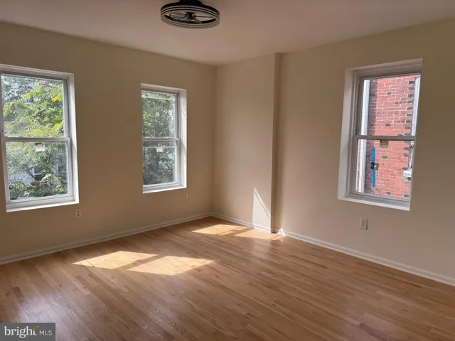 a view of empty room with wooden floor and fan