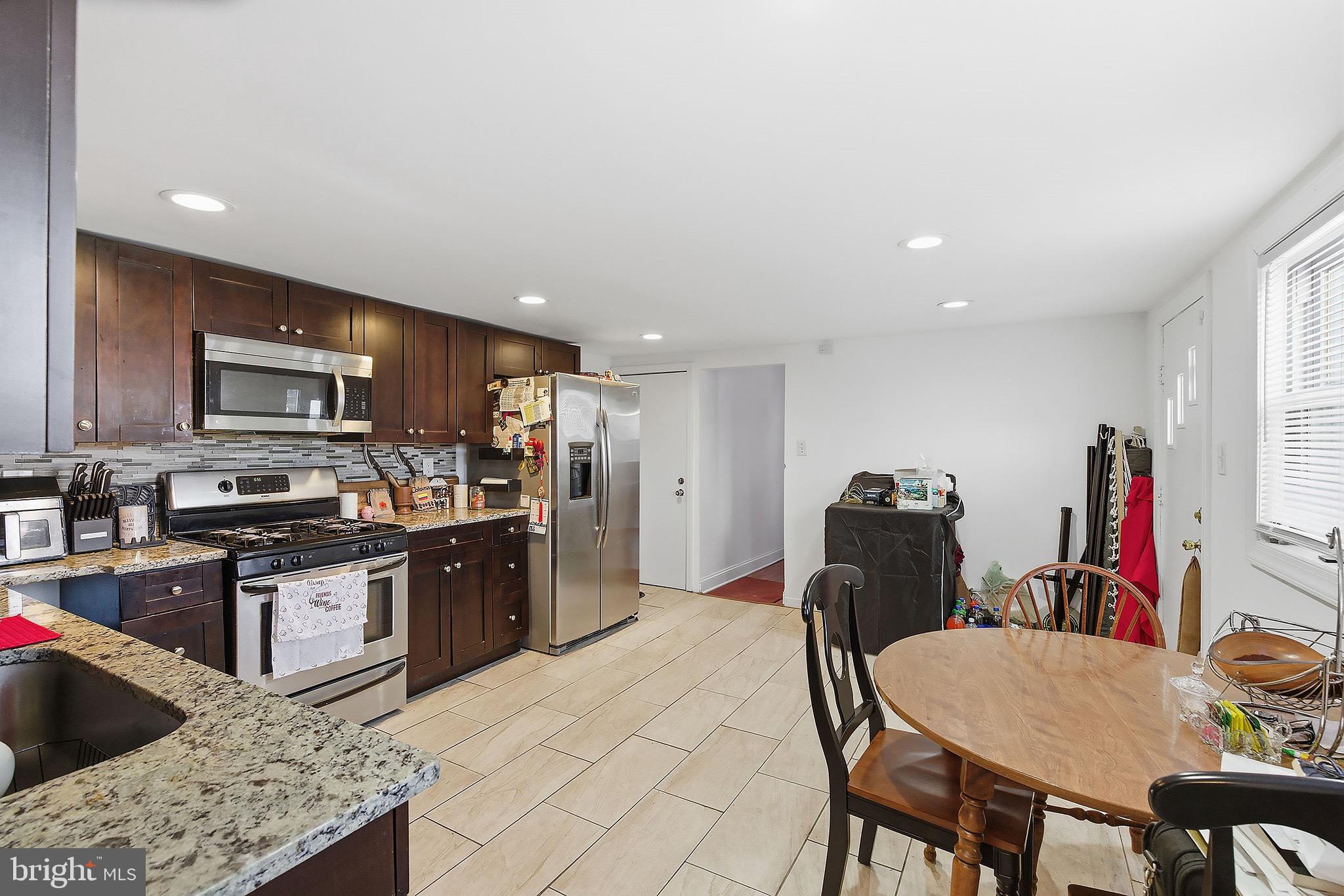 233 Ellis Street Burlington, NJ 08016 - Photo 7 of 36 a kitchen with stainless steel appliances granite countertop a sink a stove a refrigerator a microwave oven with a dining table and chairs