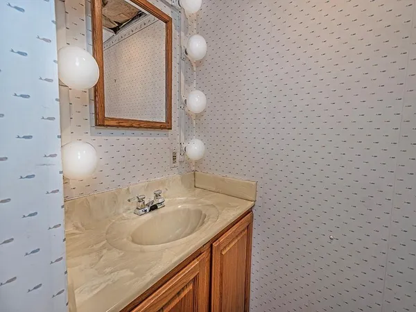 a bathroom with a sink a light fixture and a mirror