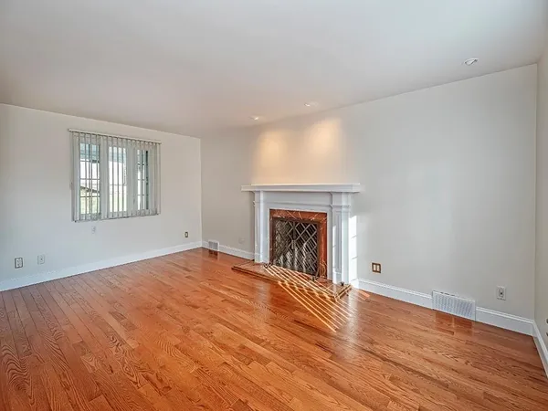 a view of empty room with wooden floor and fireplace