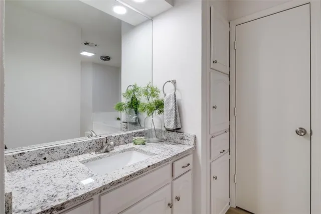 a bathroom with a granite countertop sink and a mirror