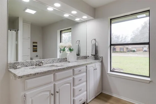a bathroom with a granite countertop sink and a window