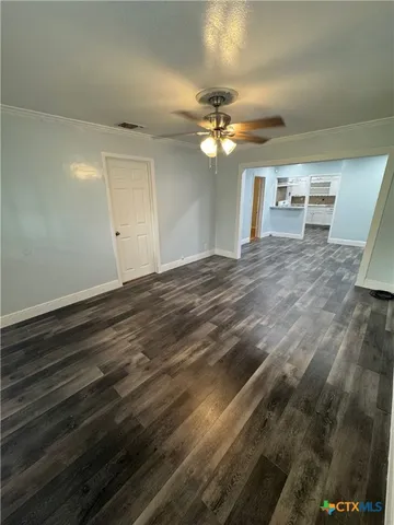 a view of an empty room with window and chandelier fan