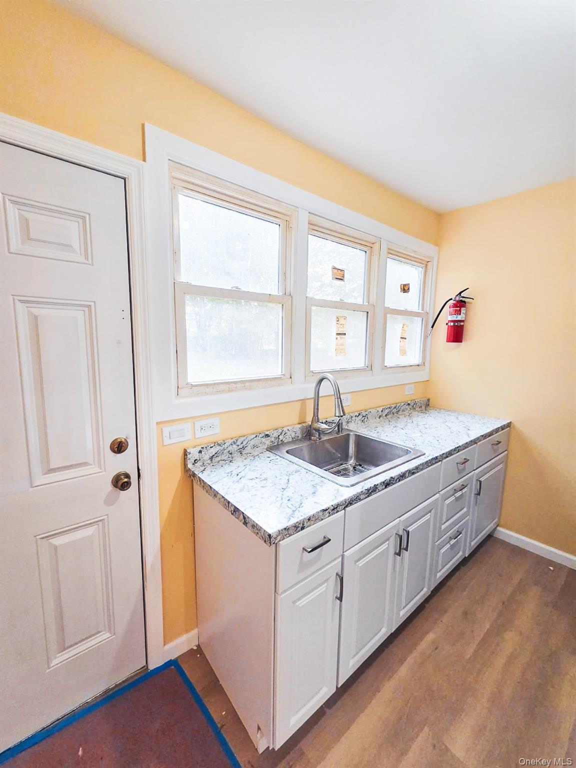 8 Cottage Street, Unit 1 Monticello, NY 12701 - Photo 2 of 9 Kitchen with light countertops, white cabinetry, healthy amount of natural light, and dark wood-type flooring