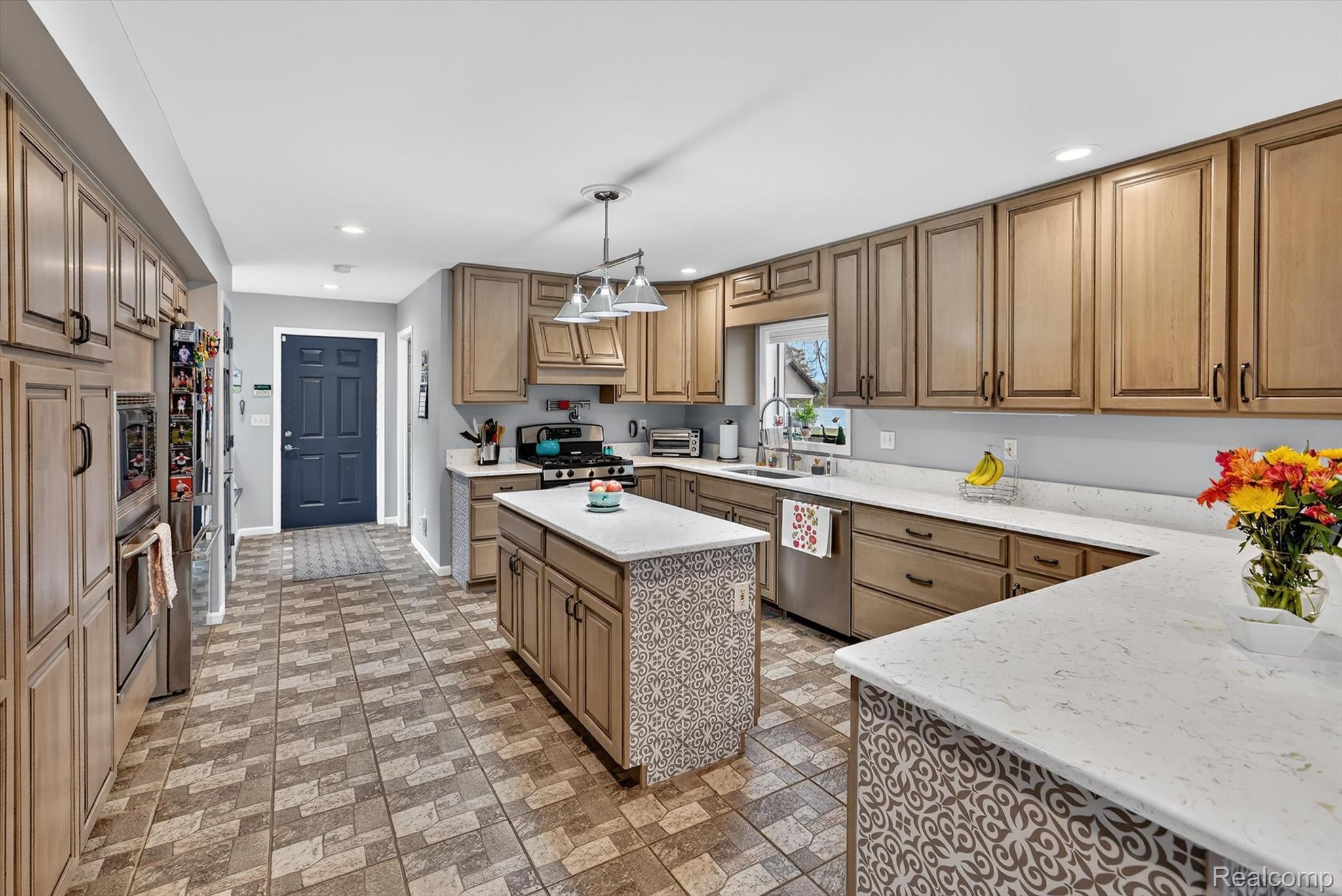 552 North McKinley Road Flushing, MI 48433 - Photo 18 of 98 Kitchen featuring wood finish cabinetry, stainless steel appliances, pendant lighting, brick patterned flooring, and a kitchen island