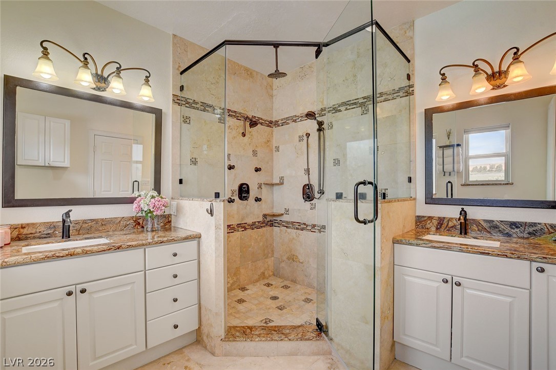 4362 Thistle Street Logandale, NV 89021 - Photo 31 of 99 Marble-clad shower with multiple heads adjoins two elegant vanity sinks.