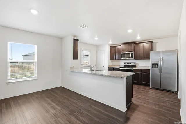 a kitchen with stainless steel appliances granite countertop a refrigerator a sink dishwasher a stove with wooden floors