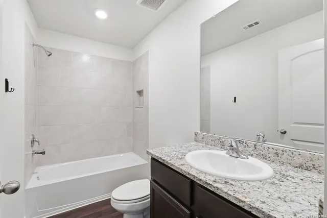 a bathroom with a granite countertop sink toilet and shower