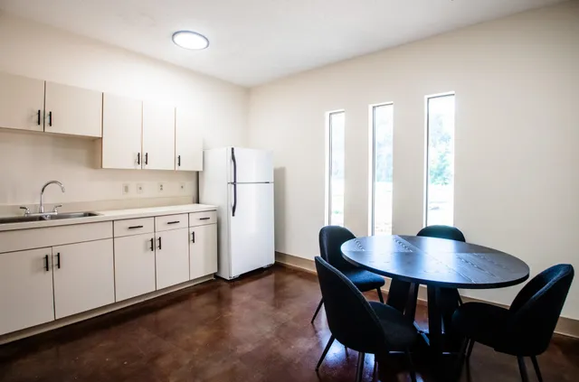 a kitchen with stainless steel appliances granite countertop a dining table chairs and a refrigerator