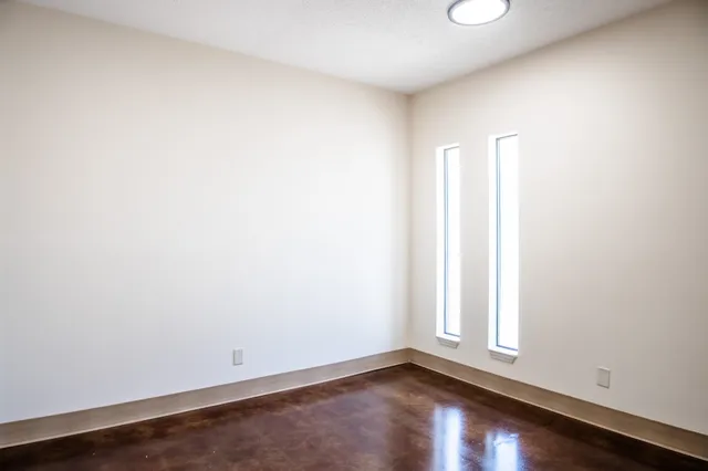 an empty room with wooden floor and window