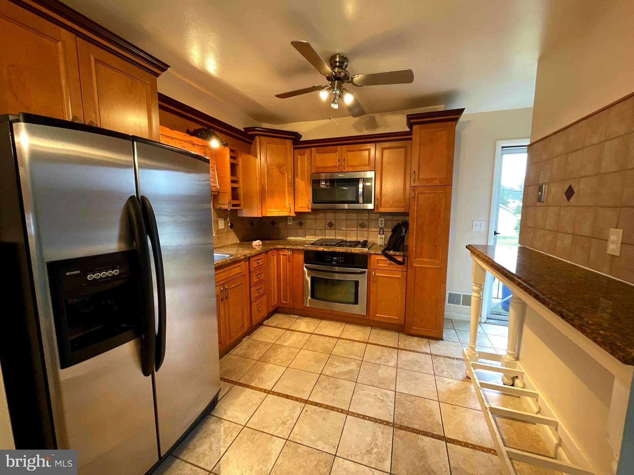 6804 Lenbern Road Baltimore, MD 21207 - Photo 3 of 17 a kitchen with stainless steel appliances granite countertop a refrigerator a stove and a sink