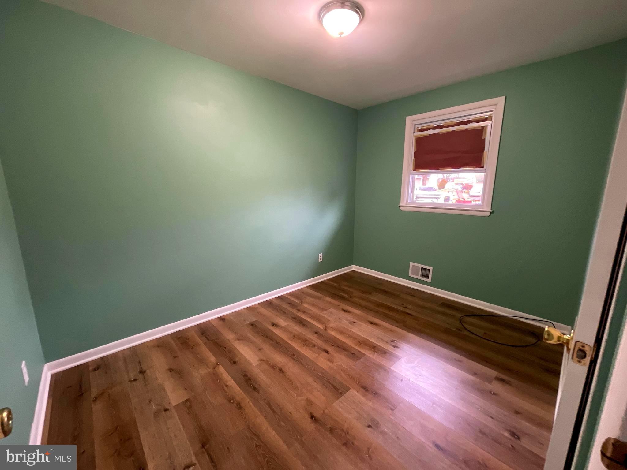 6804 Lenbern Road Baltimore, MD 21207 - Photo 6 of 17 a view of empty room with window and wooden floor