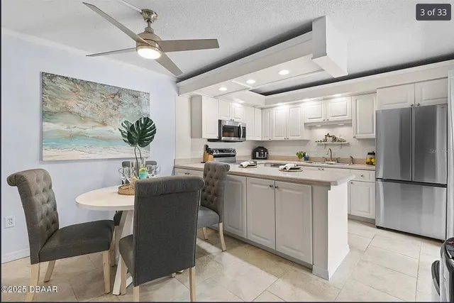 a kitchen with stainless steel appliances granite countertop a refrigerator a microwave a dining table and chairs