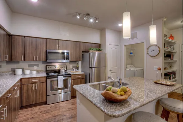 a kitchen with granite countertop a sink cabinets and stainless steel appliances