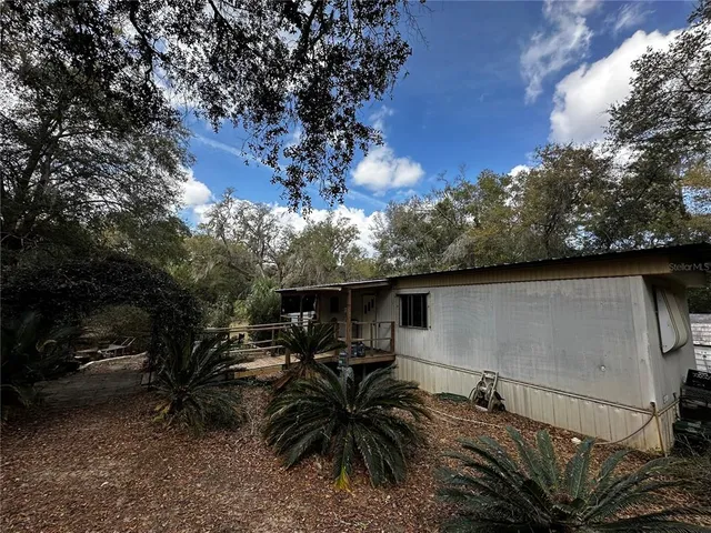 a backyard of a house with table and chairs under an umbrella