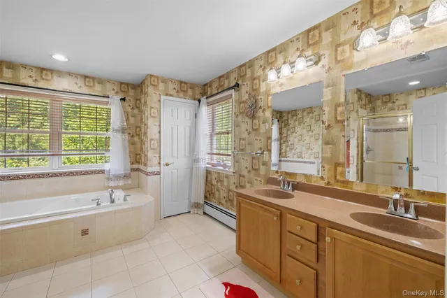 a spacious bathroom with a double vanity sink a mirror and a bathtub