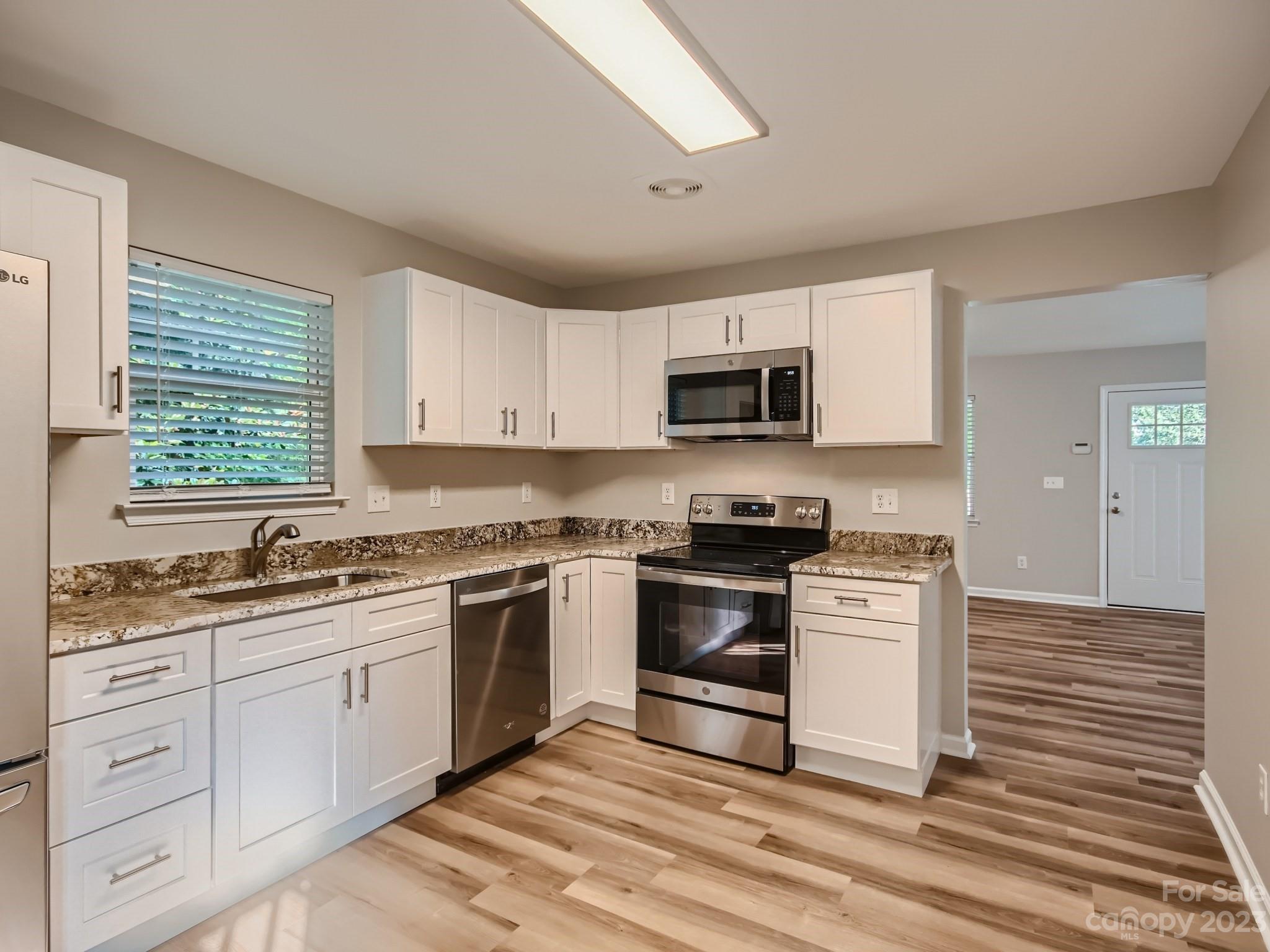 6608 Love Ridge Lane Charlotte, NC 28213 - Photo 10 of 28 a kitchen with stainless steel appliances granite countertop a stove top oven a sink dishwasher and white cabinets with wooden floor