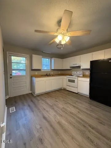 a view of a kitchen with a sink dishwasher oven window and wooden floor