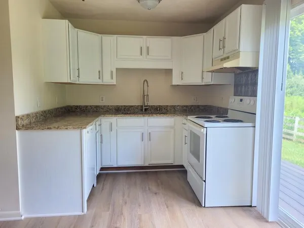 a kitchen with granite countertop white cabinets and white appliances