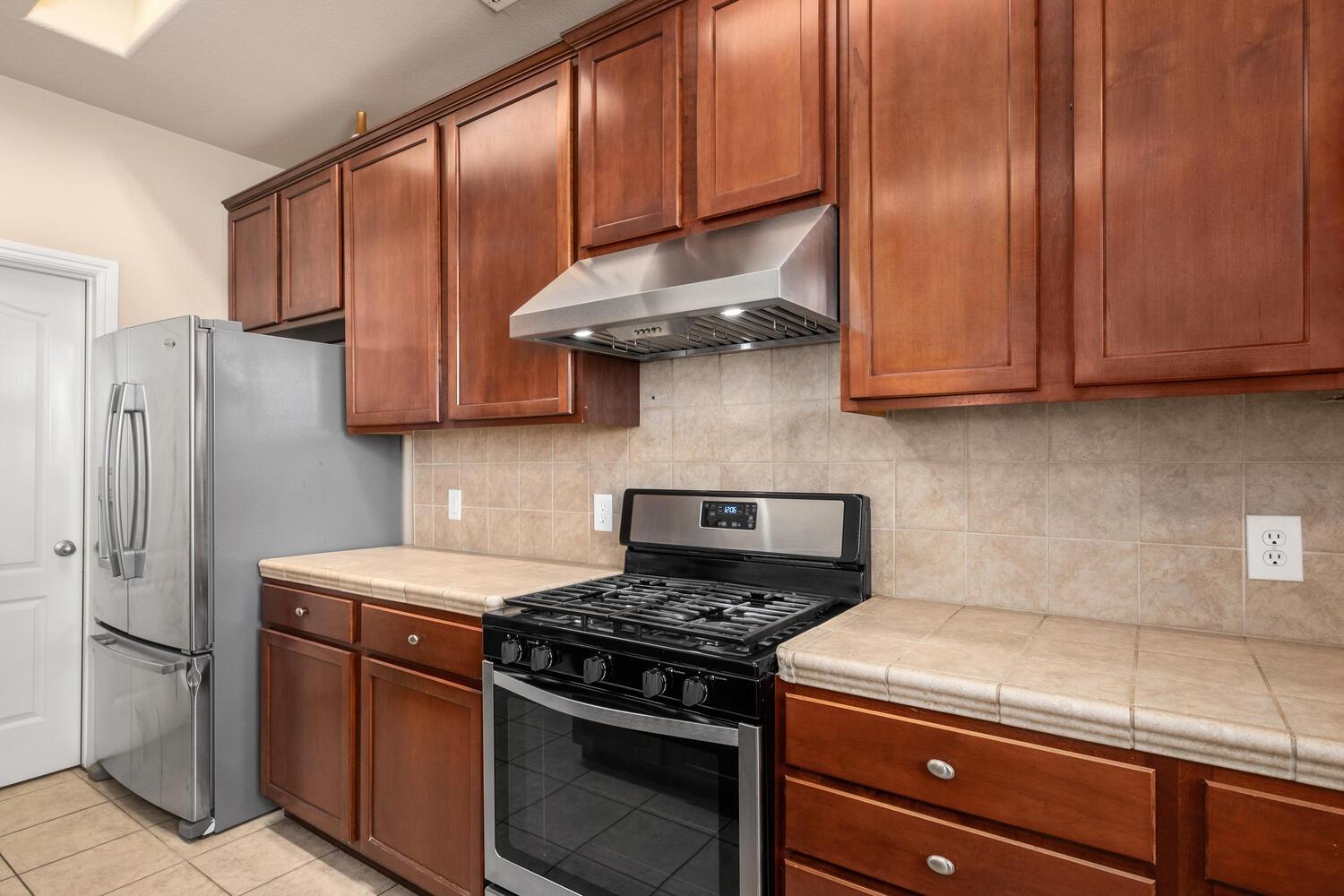 1182 Carson Avenue Clovis, CA 93611 - Photo 15 of 38 a kitchen with stainless steel appliances granite countertop a stove a refrigerator and a cabinets