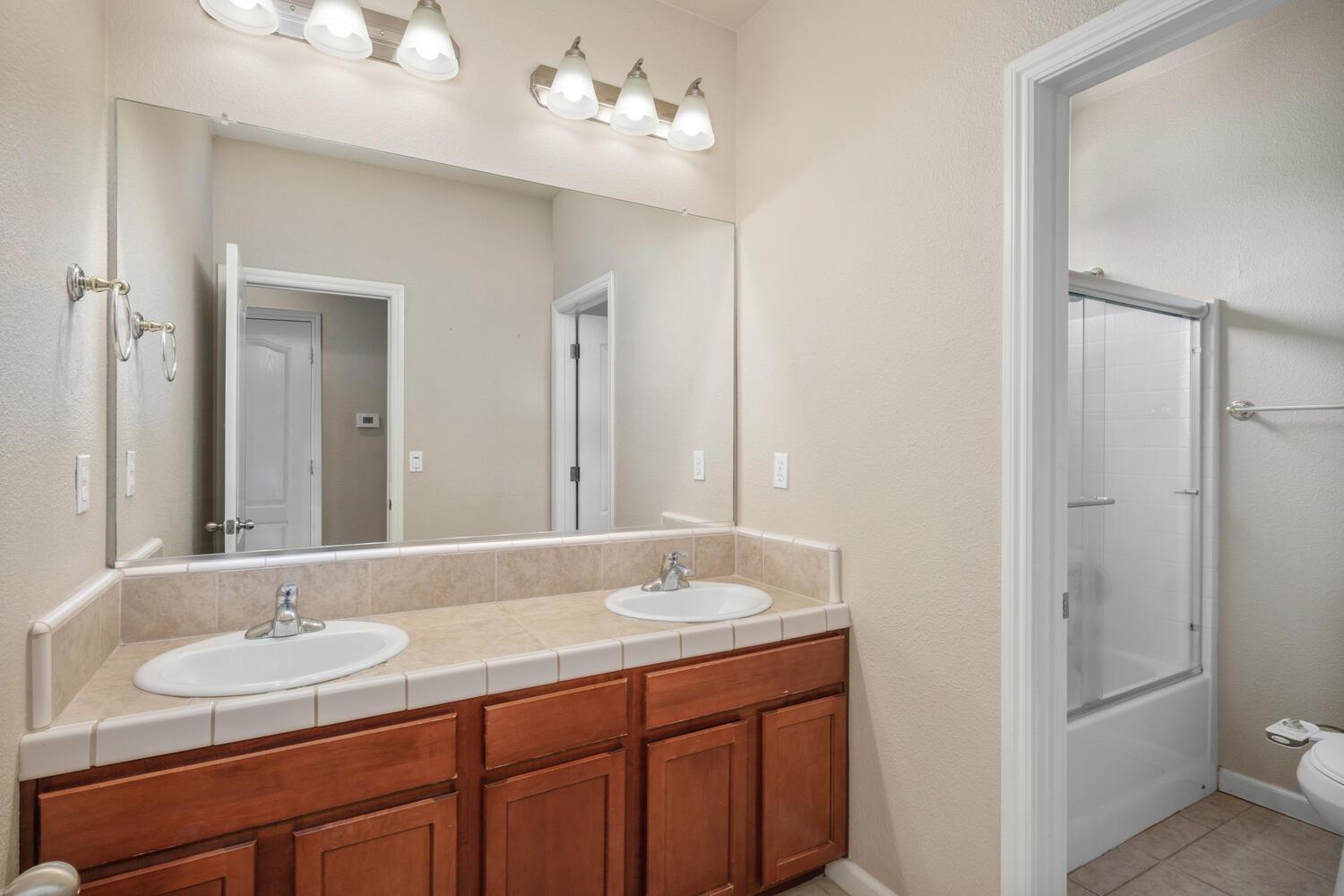 1182 Carson Avenue Clovis, CA 93611 - Photo 28 of 38 a bathroom with double vanity sinks a vanity a lamp and a mirror