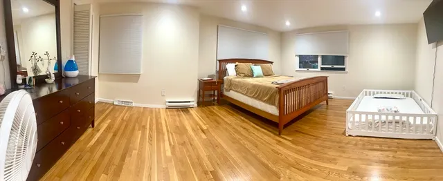 a spacious bedroom with a bed and wooden floor