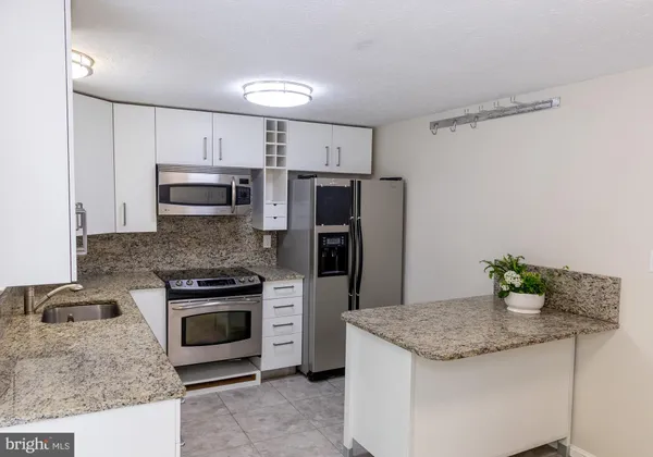 a kitchen with kitchen island granite countertop a stove and a sink