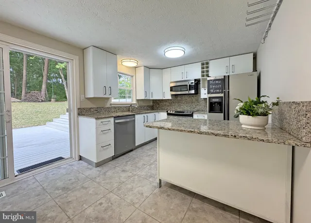 a kitchen with kitchen island granite countertop a stove top oven a sink a counter space and cabinets