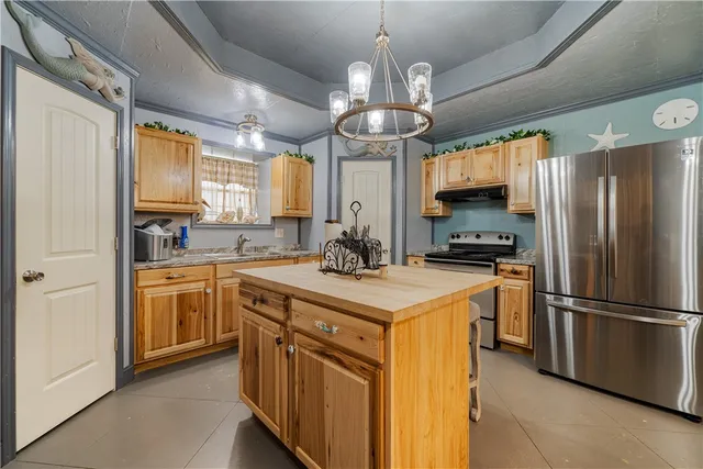 a kitchen with stainless steel appliances granite countertop a sink a stove a refrigerator cabinets and chairs