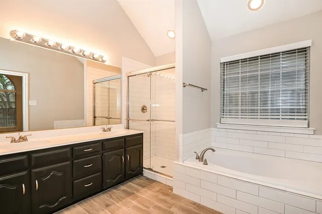 a bathroom with a tub a sink double vanity and a mirror