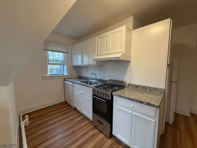 a kitchen with granite countertop white cabinets and white appliances